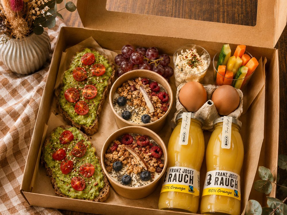 Balancebox mit Avocadobroten, Müsli, Gemüsesticks mit Dip, Obst, Eiern und Fruchtsäften