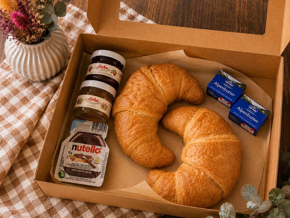 Süßer Morgen mit zwei Croissants, Butter, Marmelade, Honig und Nutella